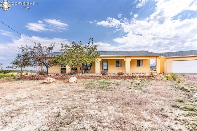 ranch-style home with covered porch, an attached garage, and stucco siding