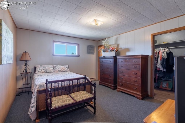 bedroom featuring a walk in closet, dark carpet, a closet, and a baseboard heating unit