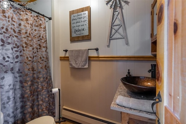 bathroom featuring a shower with shower curtain, sink, and a baseboard heating unit