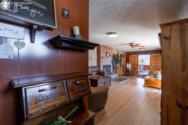 living room with ceiling fan, a fireplace, and light wood-type flooring