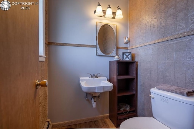 bathroom featuring toilet, sink, and tile walls