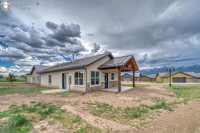 306 Fox Run E, Silver Cliff, CO 81252 - rear view of property with a standing seam roof, a metal roof, a patio, stone siding, and stucco siding