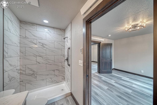 306 Fox Run E, Silver Cliff, CO 81252 - bathroom featuring a textured ceiling, wood finished floors, tiled shower, vanity, and a textured wall