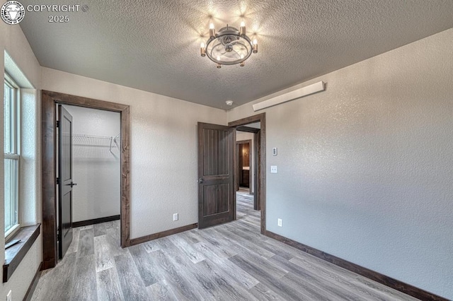 306 Fox Run E, Silver Cliff, CO 81252 - unfurnished bedroom with a textured wall, light wood-style floors, a textured ceiling, multiple windows, and a spacious closet