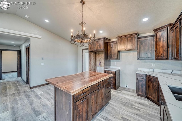 306 Fox Run E, Silver Cliff, CO 81252 - kitchen with wooden counters, a chandelier, light wood-style flooring, dark brown cabinets, and lofted ceiling