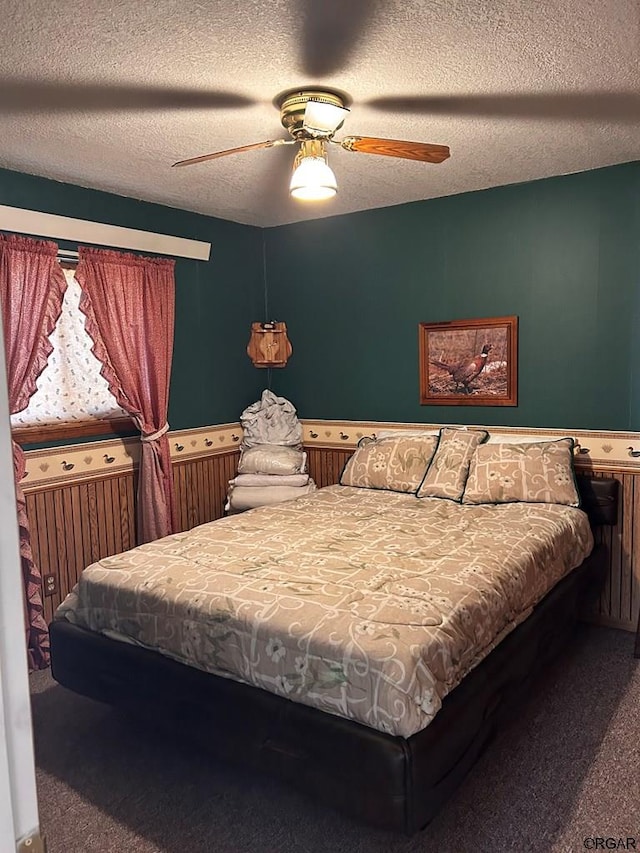 bedroom with ceiling fan, carpet flooring, and a textured ceiling