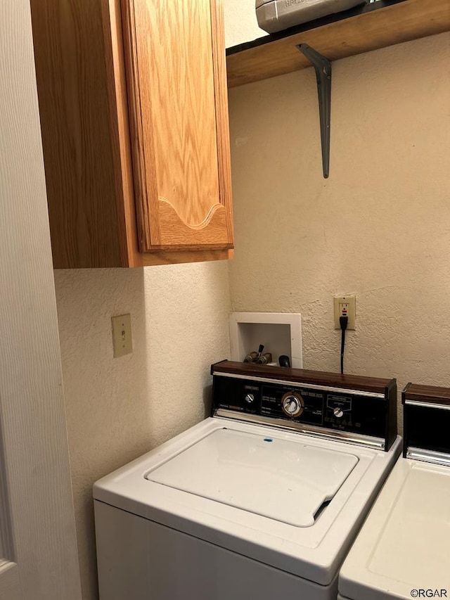 laundry area featuring washer and clothes dryer and cabinets