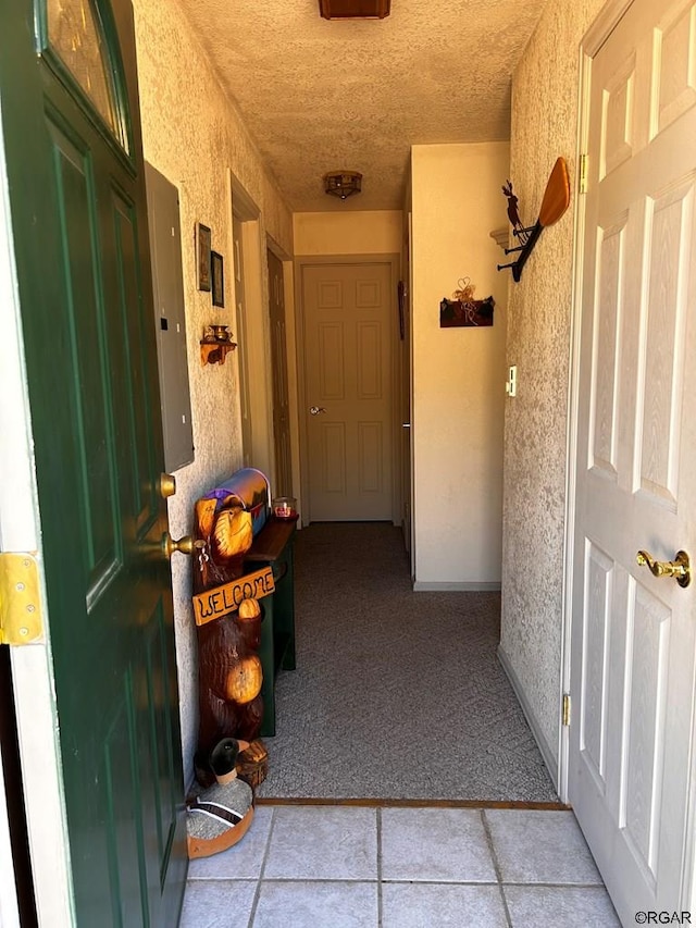 hallway with light colored carpet, electric panel, and a textured ceiling