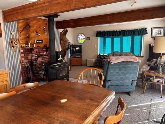 dining room with beam ceiling, carpet, and a wood stove