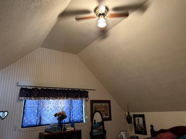 bedroom with a textured ceiling, vaulted ceiling, and ceiling fan