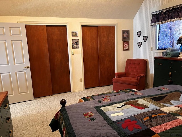 bedroom with multiple closets, vaulted ceiling, and light carpet