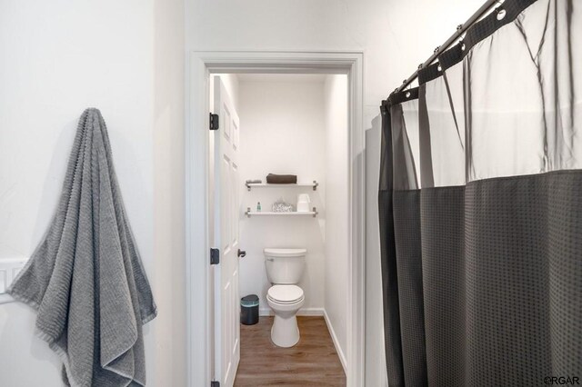 bathroom featuring wood-type flooring, toilet, and walk in shower