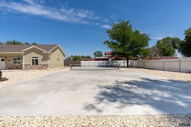 view of side of home featuring tennis court