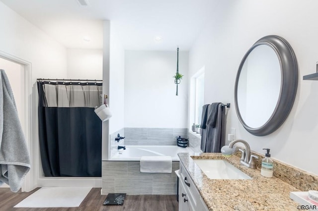 bathroom with tiled tub, vanity, and hardwood / wood-style floors