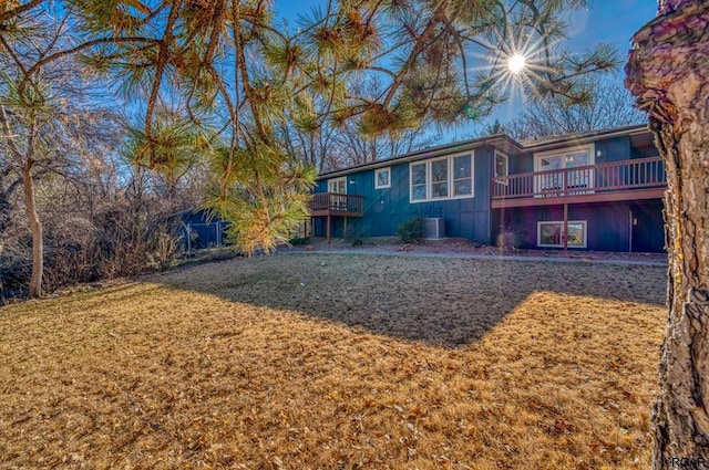 rear view of property with a wooden deck, a yard, and central AC