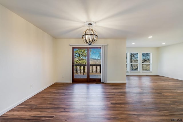 spare room with dark hardwood / wood-style floors, a wealth of natural light, and a notable chandelier