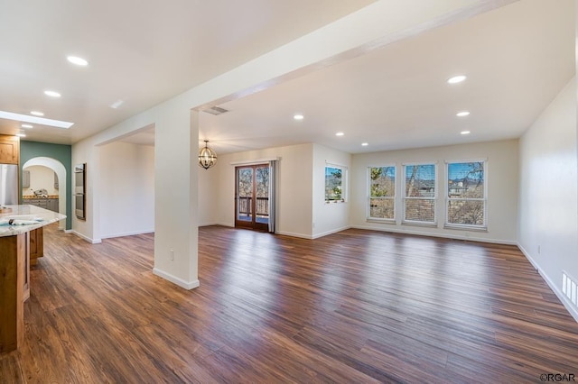 unfurnished living room with an inviting chandelier and dark hardwood / wood-style floors