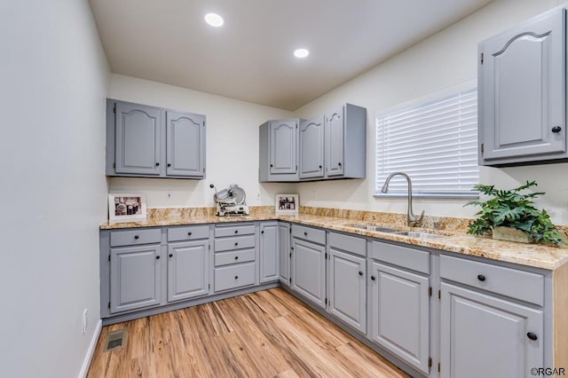 kitchen with light wood-type flooring, sink, and gray cabinetry