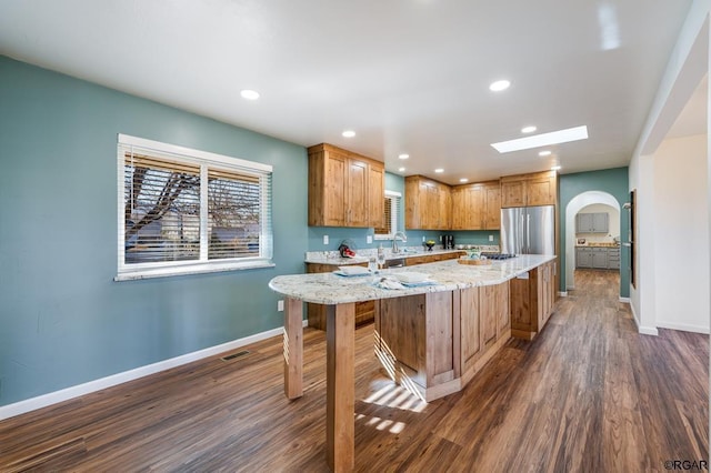 kitchen featuring sink, dark hardwood / wood-style floors, light stone countertops, and stainless steel refrigerator