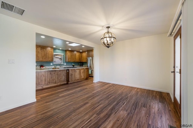 kitchen featuring decorative light fixtures, a chandelier, stainless steel refrigerator, dark hardwood / wood-style flooring, and a wealth of natural light