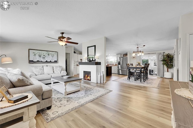 1431 Pine St, Canon City, CO 81212 - living room featuring a ceiling fan, a chandelier, light wood-style flooring, and a lit fireplace