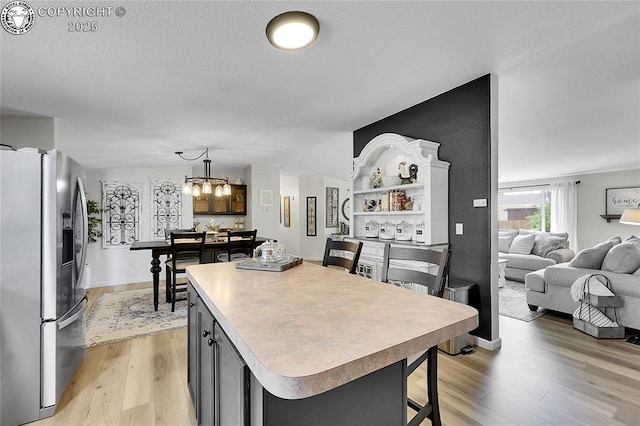1431 Pine St, Canon City, CO 81212 - kitchen with stainless steel refrigerator with ice dispenser, light wood-type flooring, light countertops, open floor plan, and a kitchen island