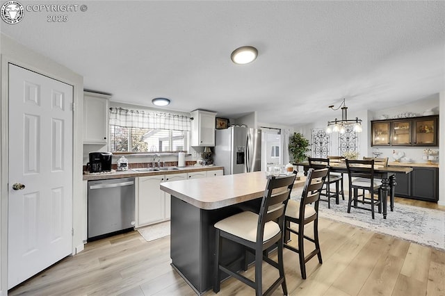 1431 Pine St, Canon City, CO 81212 - kitchen featuring stainless steel appliances, light wood-type flooring, light countertops, a kitchen breakfast bar, and a textured ceiling