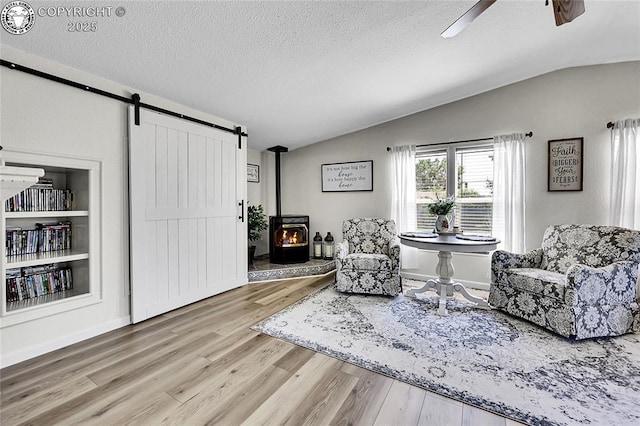 1431 Pine St, Canon City, CO 81212 - living area with lofted ceiling, wood finished floors, a ceiling fan, a textured ceiling, and a barn door