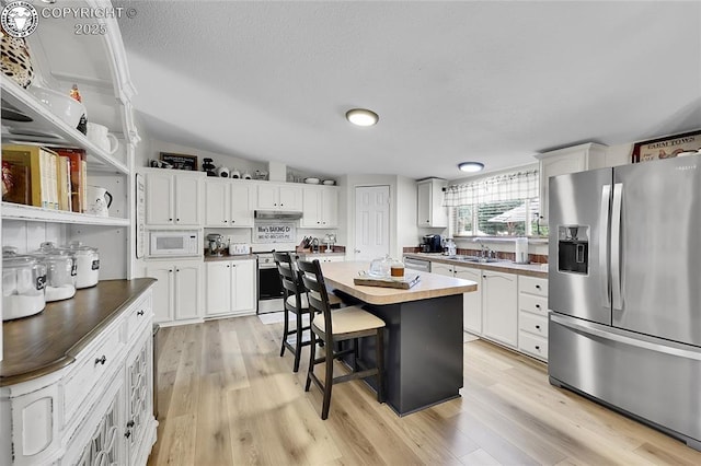 1431 Pine St, Canon City, CO 81212 - kitchen featuring stainless steel appliances, white cabinets, light wood-type flooring, and a textured ceiling