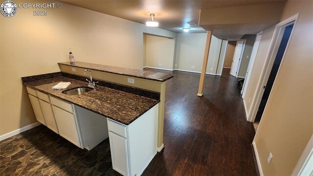 7465 Sun Prairie Dr, Colorado Springs, CO 80925 - kitchen with a peninsula, white cabinets, dark stone countertops, and dark wood finished floors