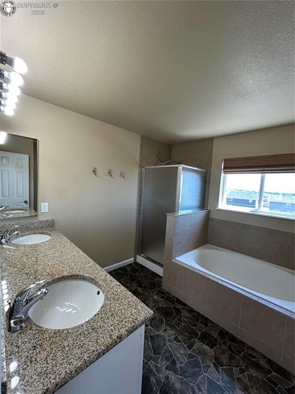 7465 Sun Prairie Dr, Colorado Springs, CO 80925 - bathroom featuring double vanity, a bath, a stall shower, and a textured ceiling