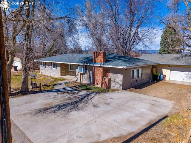 ranch-style house with a garage, driveway, and a chimney