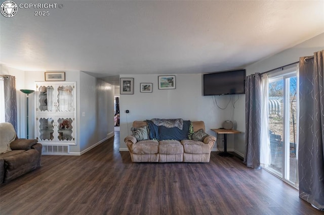 living room featuring visible vents, baseboards, and wood finished floors