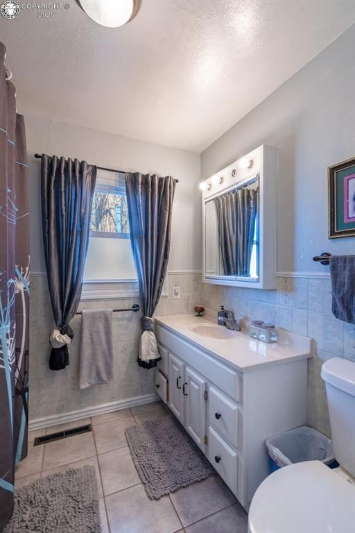 bathroom with a textured ceiling, toilet, vanity, visible vents, and tile patterned floors