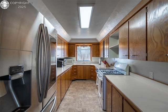 kitchen featuring open shelves, light countertops, brown cabinetry, a sink, and white appliances