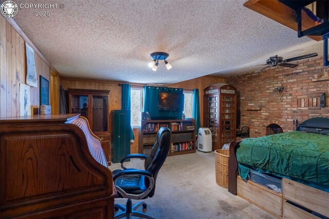 bedroom with a textured ceiling, carpet floors, brick wall, and wooden walls