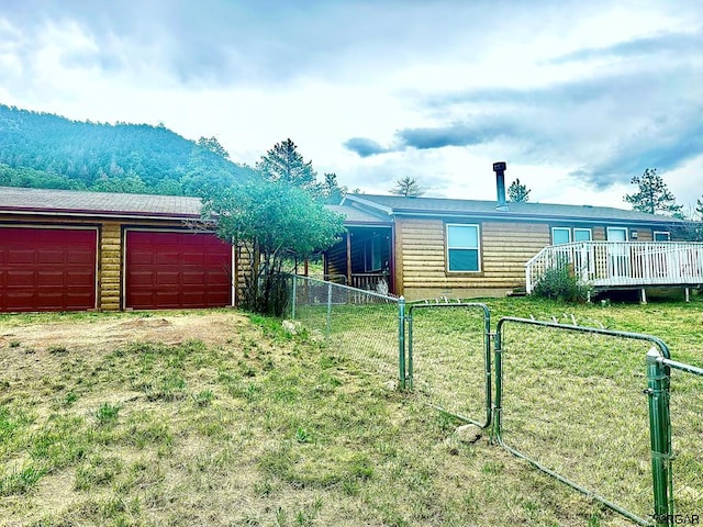 view of property exterior with a deck with mountain view and a lawn