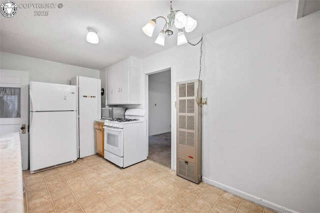 kitchen featuring white appliances, a heating unit, white cabinets, light countertops, and a notable chandelier