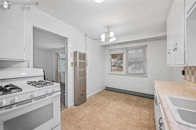 kitchen featuring a notable chandelier, white gas range, light countertops, a baseboard heating unit, and white cabinets