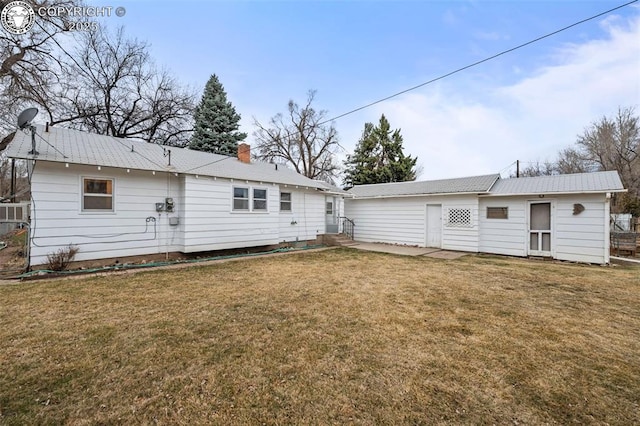 rear view of house with entry steps, a yard, and a chimney