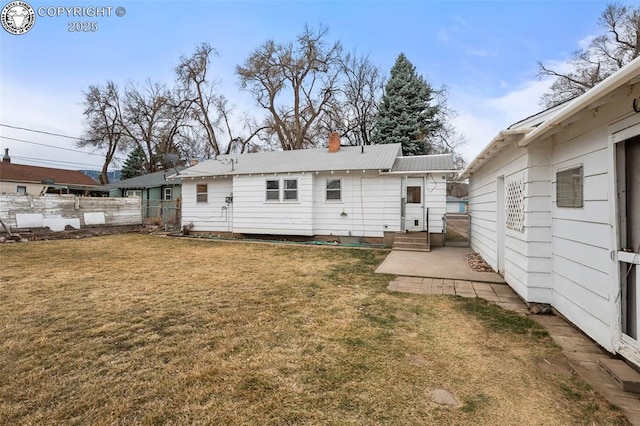 rear view of property featuring entry steps, a patio area, fence, and a lawn