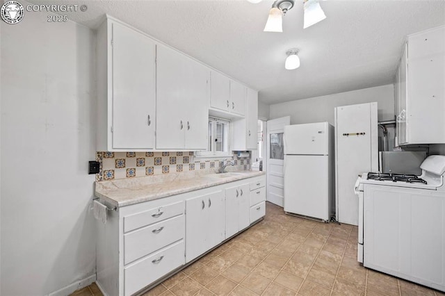 kitchen featuring white appliances, light countertops, a sink, and white cabinetry