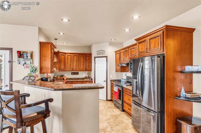 kitchen with appliances with stainless steel finishes, a kitchen bar, kitchen peninsula, and dark stone counters