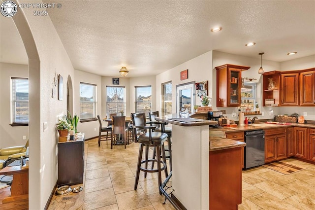 kitchen featuring black dishwasher, a kitchen bar, kitchen peninsula, and decorative light fixtures