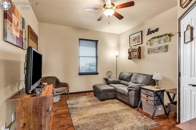 living room featuring dark wood-type flooring and ceiling fan