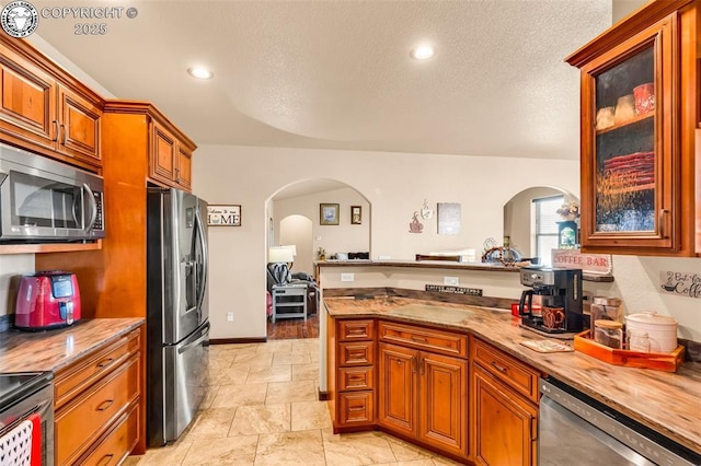 kitchen featuring appliances with stainless steel finishes, a textured ceiling, and light stone counters