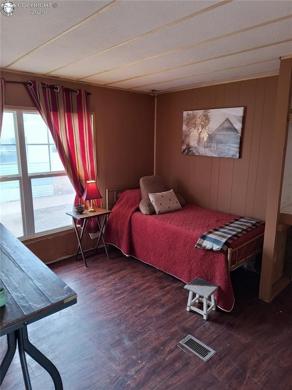 bedroom featuring dark hardwood / wood-style flooring and wood walls