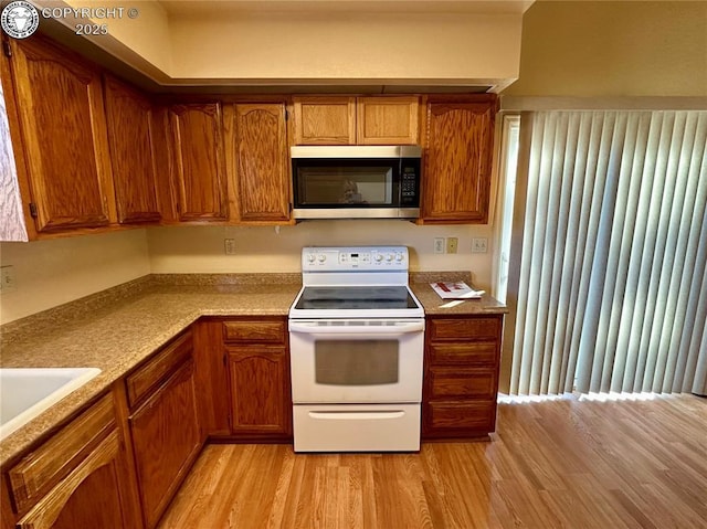 kitchen with sink, white electric stove, and light hardwood / wood-style floors