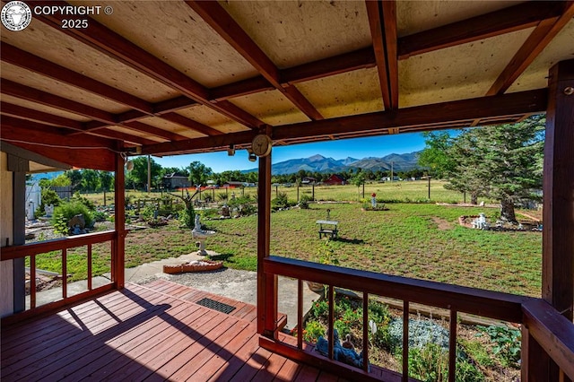 deck featuring a rural view, a mountain view, and a yard