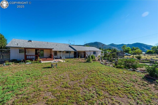 rear view of property featuring a mountain view and a yard